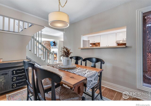 dining space with crown molding, stairway, wood finished floors, and baseboards