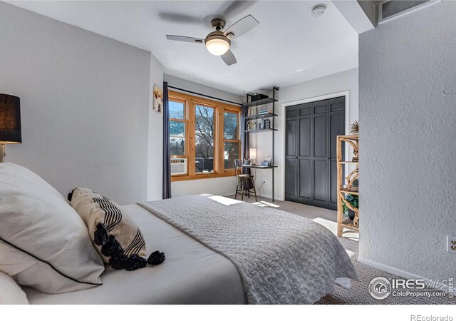 carpeted bedroom featuring ceiling fan, a textured wall, visible vents, baseboards, and a closet