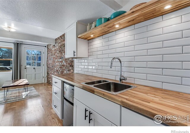 kitchen featuring a sink, wood counters, white cabinets, dishwasher, and light wood finished floors