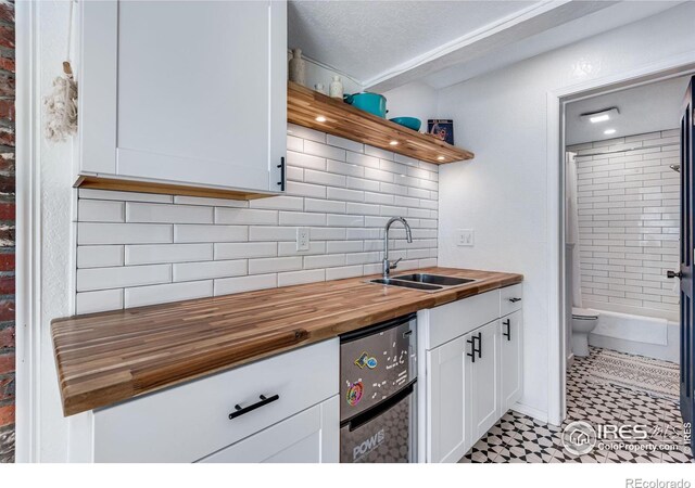 kitchen featuring a sink, wood counters, white cabinetry, open shelves, and tasteful backsplash