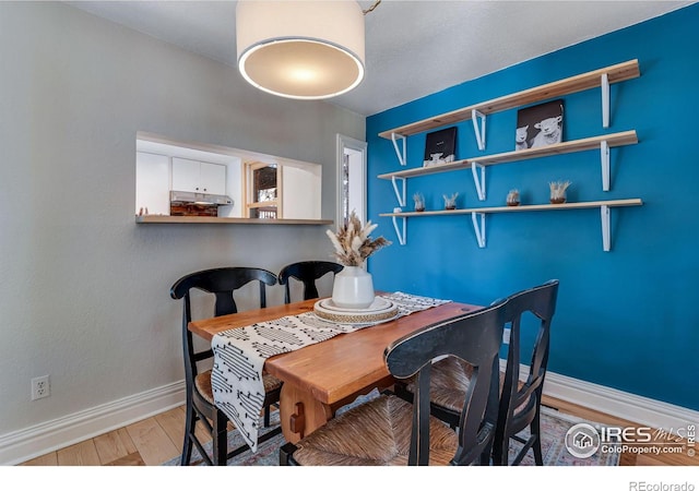 dining space with baseboards and light wood finished floors