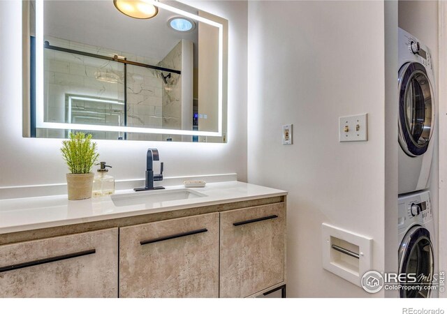 bathroom featuring stacked washer and dryer, vanity, and a shower stall