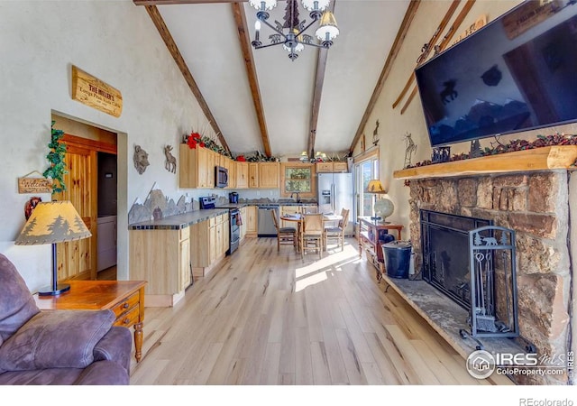 living area featuring beam ceiling, high vaulted ceiling, light wood-style floors, a stone fireplace, and a chandelier