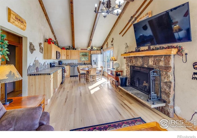 living area with light wood-style flooring, a chandelier, a fireplace, and lofted ceiling with beams