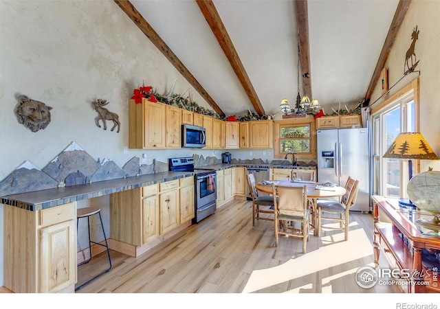 kitchen featuring lofted ceiling with beams, stainless steel appliances, light wood-type flooring, light brown cabinetry, and dark countertops