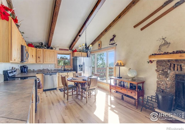 kitchen featuring vaulted ceiling with beams, stainless steel appliances, light brown cabinets, and light wood-style flooring