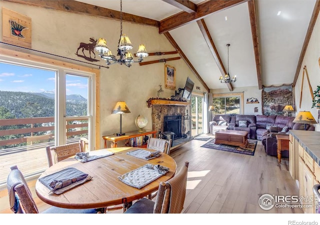 dining space with high vaulted ceiling, a notable chandelier, a fireplace, wood finished floors, and beamed ceiling