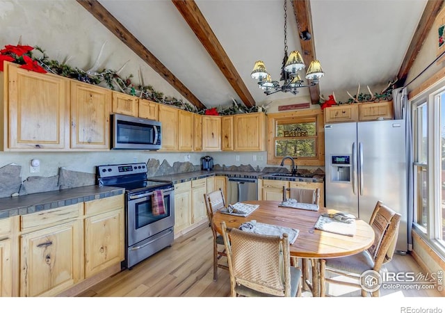 kitchen featuring vaulted ceiling with beams, a sink, stainless steel appliances, light wood-style floors, and a notable chandelier