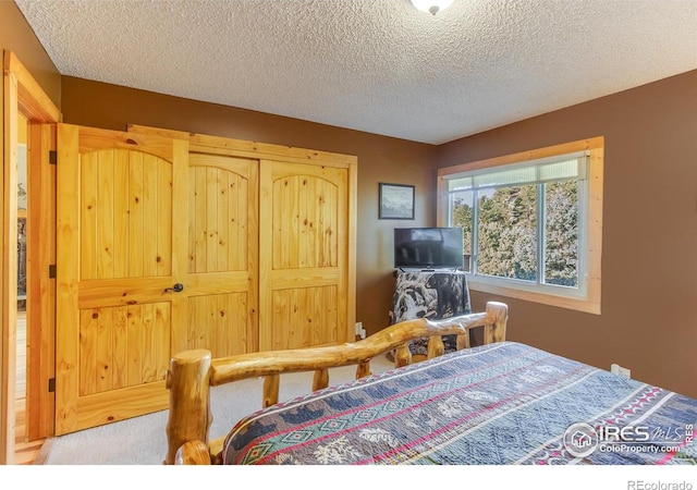 carpeted bedroom featuring a textured ceiling and a closet