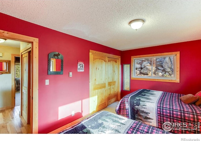 bedroom featuring a closet, a textured ceiling, and wood finished floors