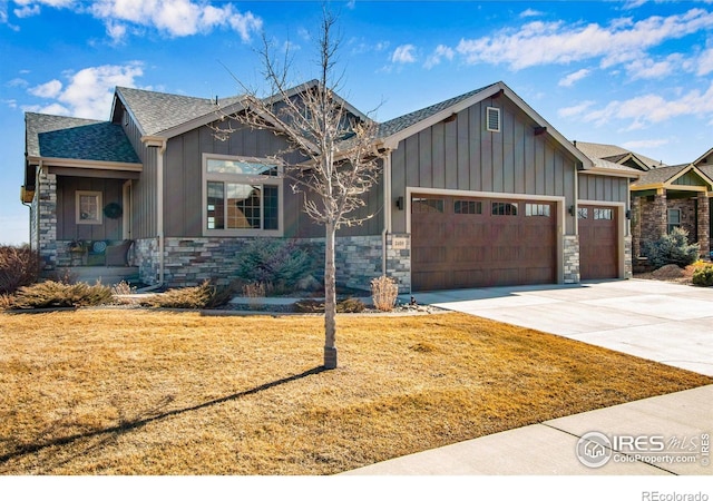 craftsman-style house featuring a garage, stone siding, concrete driveway, a front lawn, and board and batten siding