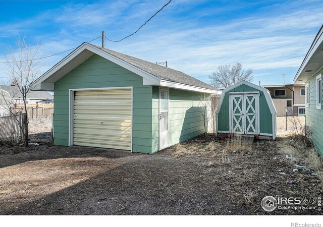 detached garage featuring dirt driveway and fence