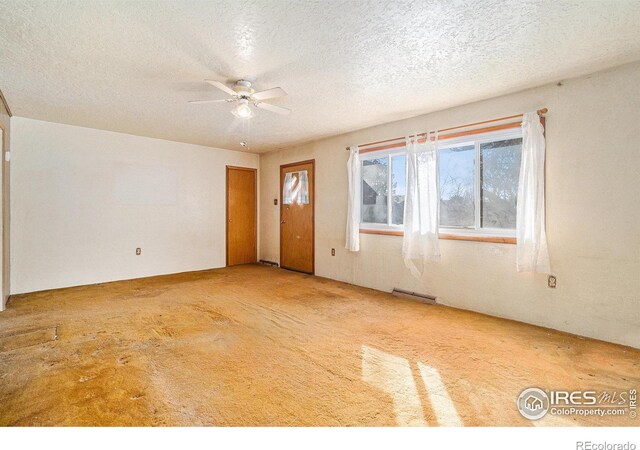 unfurnished room with visible vents, a textured ceiling, carpet flooring, and a ceiling fan