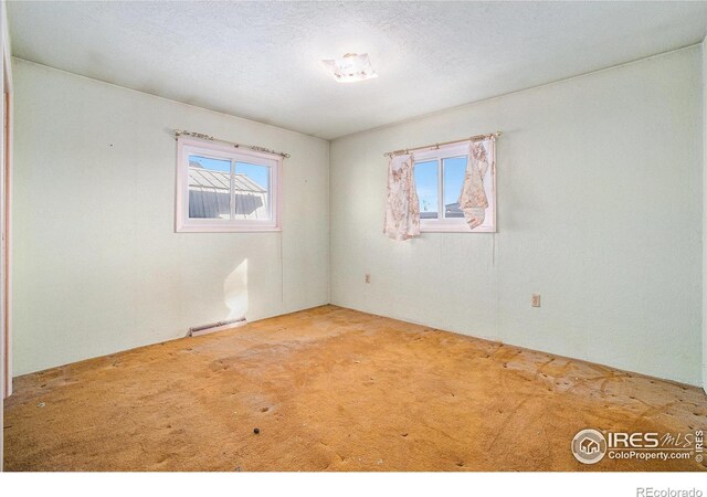 unfurnished room with carpet flooring, visible vents, and a textured ceiling