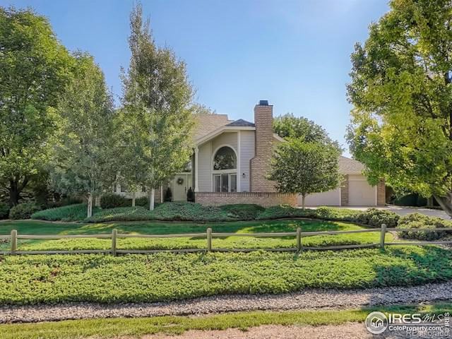 view of property hidden behind natural elements with a garage, brick siding, fence, and a front lawn