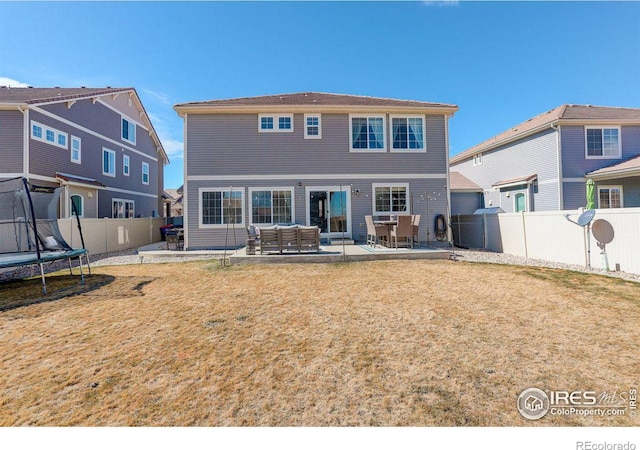 back of property featuring a patio, a yard, a trampoline, and a fenced backyard