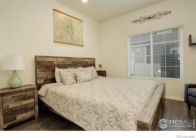 bedroom with dark wood-type flooring, vaulted ceiling, and baseboards