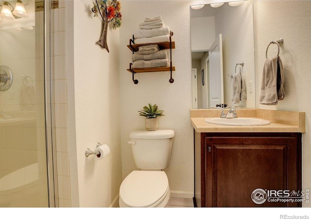 full bath featuring baseboards, a tile shower, vanity, and toilet