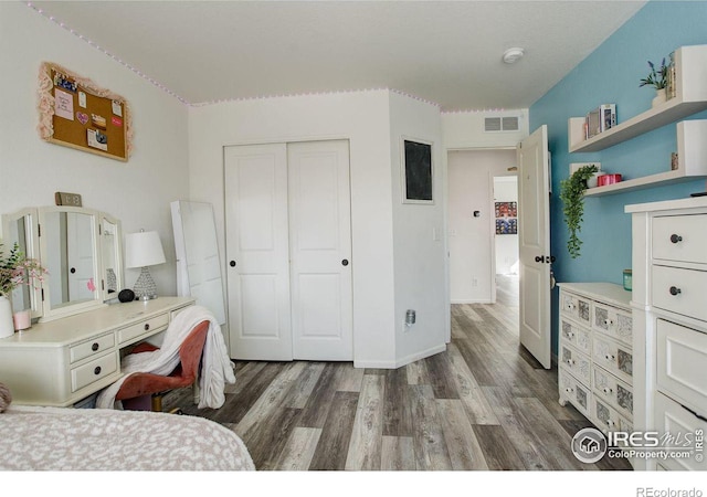 bedroom featuring a closet, visible vents, baseboards, and wood finished floors