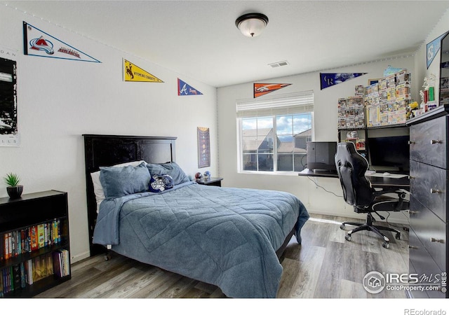 bedroom with baseboards, visible vents, and wood finished floors