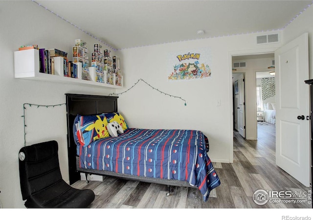 bedroom featuring wood finished floors and visible vents