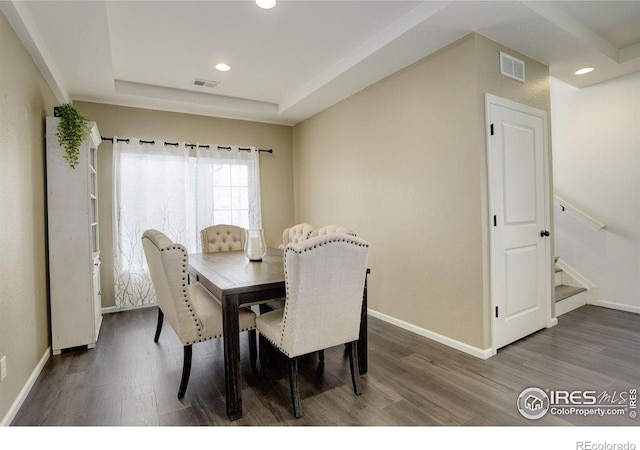 dining room featuring a tray ceiling, recessed lighting, visible vents, wood finished floors, and baseboards