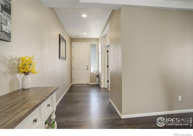 interior space featuring recessed lighting, baseboards, dark wood-type flooring, and a textured wall