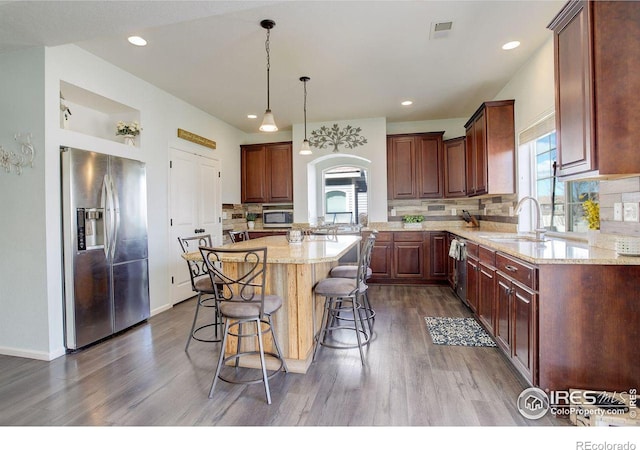 kitchen with a breakfast bar, visible vents, appliances with stainless steel finishes, dark wood-type flooring, and a sink