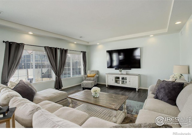 living room with baseboards, dark wood-style flooring, a raised ceiling, and recessed lighting