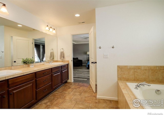 bathroom with double vanity, a garden tub, visible vents, and a sink