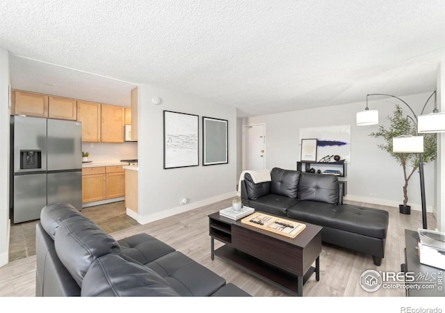 living area featuring light wood-type flooring, a textured ceiling, and baseboards