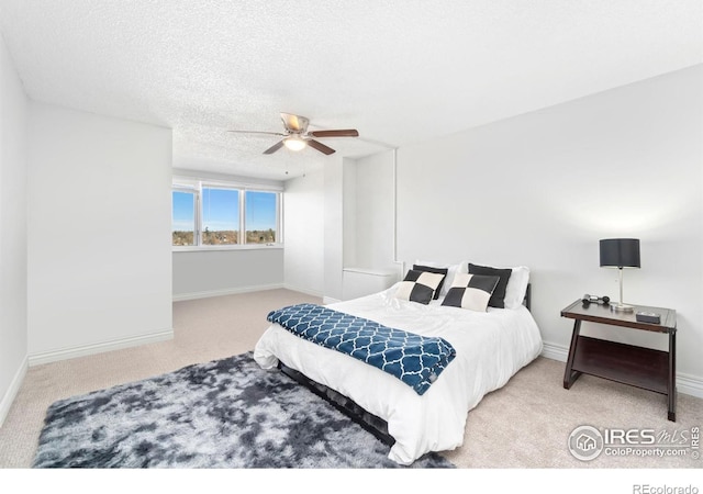 carpeted bedroom featuring a textured ceiling, a ceiling fan, and baseboards