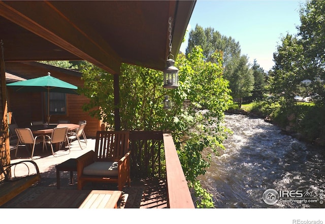 wooden terrace with outdoor dining space and a water view