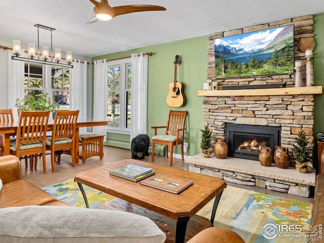 interior space featuring a baseboard heating unit, a fireplace, baseboard heating, and ceiling fan with notable chandelier