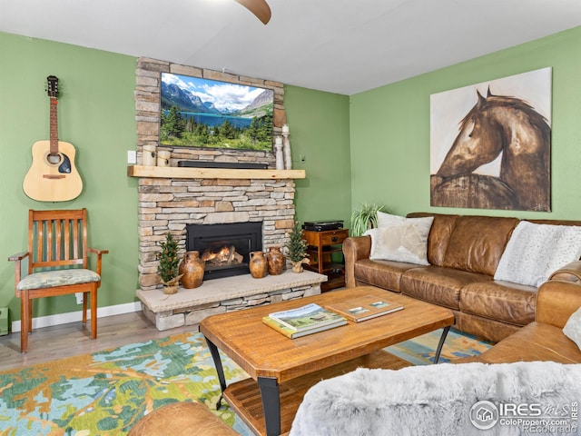 living area with a stone fireplace, wood finished floors, and baseboards