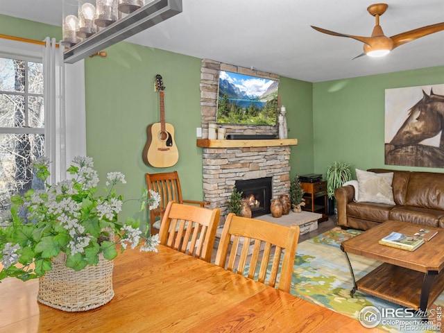 living area featuring a ceiling fan and a stone fireplace