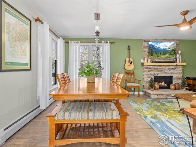 dining space with baseboards, a fireplace, a baseboard heating unit, and wood finished floors