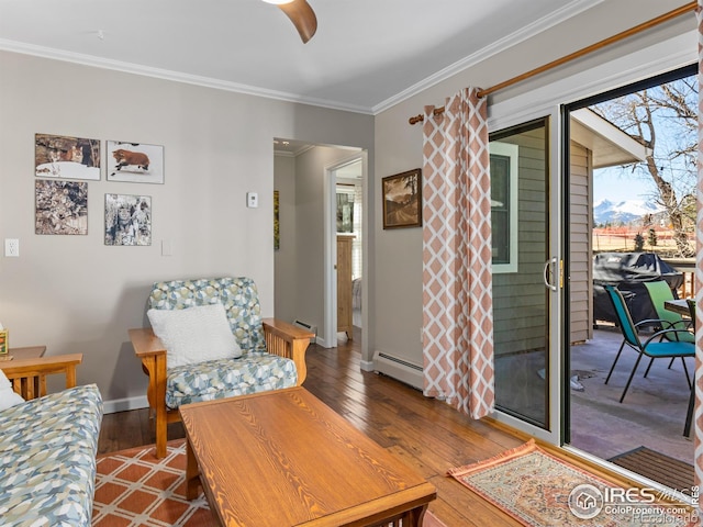 sitting room with a baseboard heating unit, wood-type flooring, and crown molding