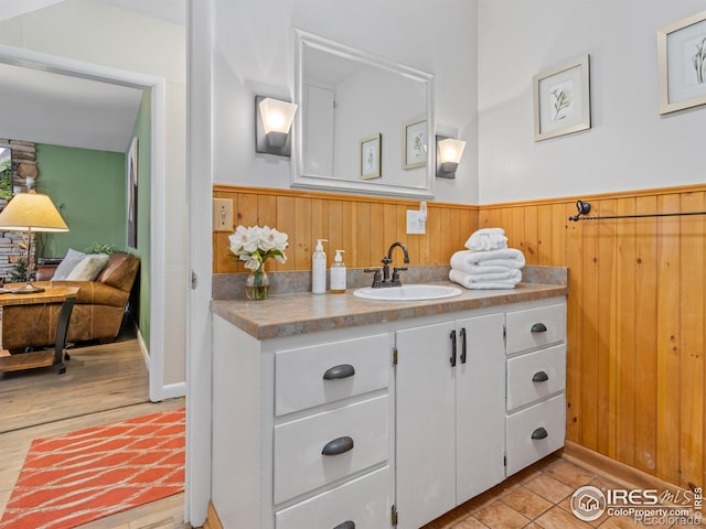 bathroom featuring a wainscoted wall, wood walls, vanity, and wood finished floors