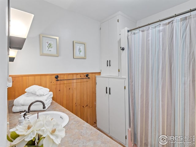 full bathroom with curtained shower, wood walls, and wainscoting