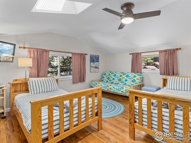 bedroom featuring lofted ceiling with skylight, a ceiling fan, and wood finished floors