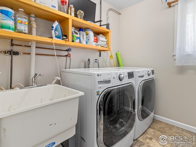 washroom with laundry area, independent washer and dryer, a sink, and baseboards