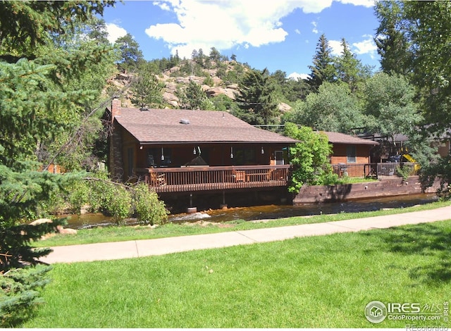 view of front of house with a chimney, a front lawn, and a wooden deck