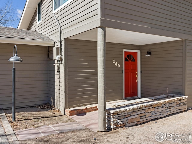 entrance to property featuring roof with shingles