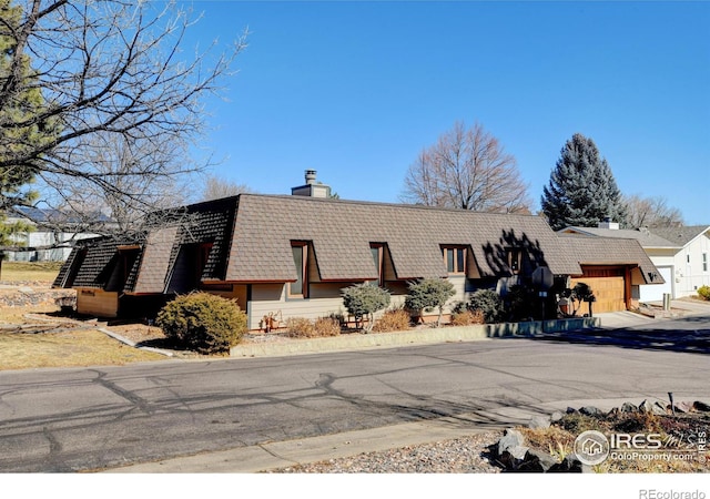 view of side of property featuring a garage and a chimney