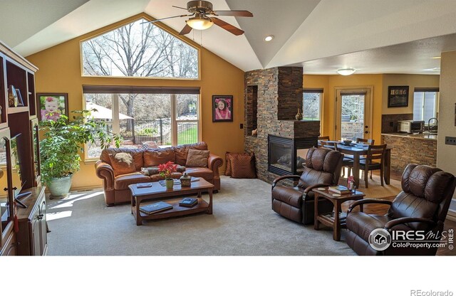 living room featuring high vaulted ceiling, carpet, a fireplace, and ceiling fan