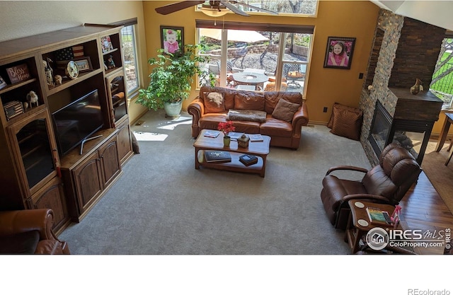 carpeted living area featuring lofted ceiling, a fireplace, and ceiling fan