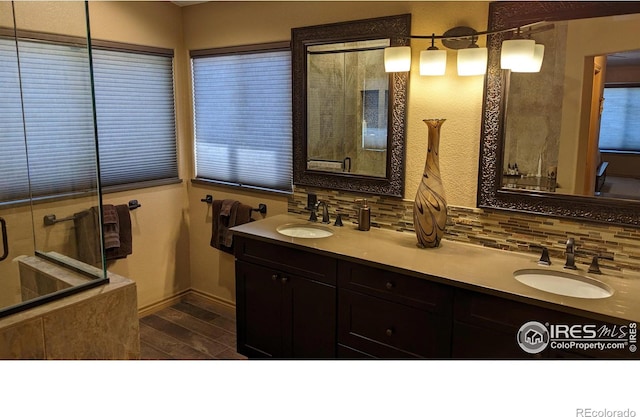 full bathroom featuring double vanity, wood finished floors, backsplash, and a sink