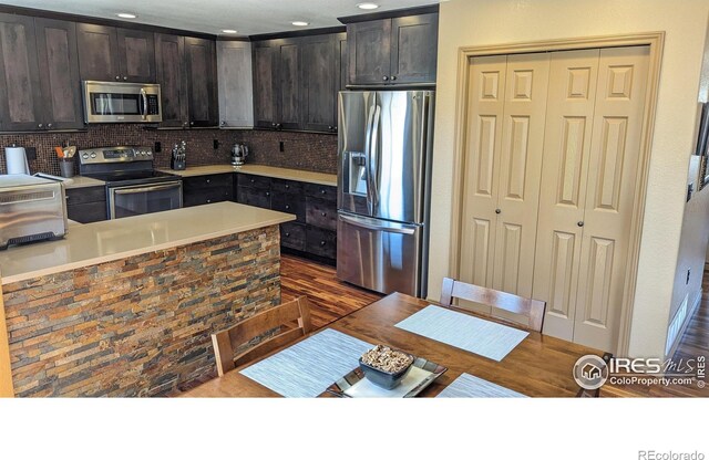 kitchen with dark brown cabinets, tasteful backsplash, stainless steel appliances, and light countertops