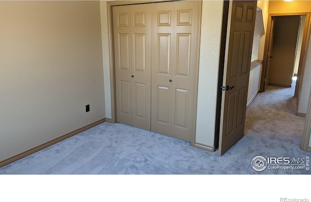 unfurnished bedroom with a closet, baseboards, and carpet flooring